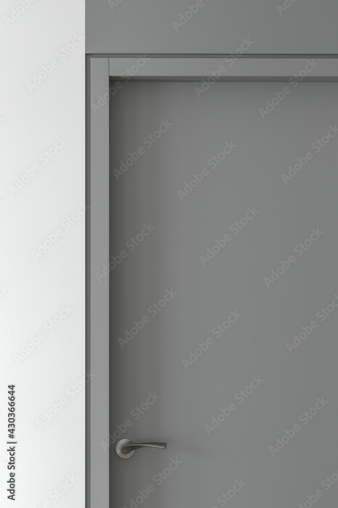 Simple Modern Grey Closed Door with Frame and grey door handle on Grey Wall in the Empty Room. Interior Design Element of contemporary interior design at modern house Simple Modern Grey Closed Door with Frame and grey door handle on Grey Wall in the Empty Room. Interior Design Element of contemporary interior design at modern house