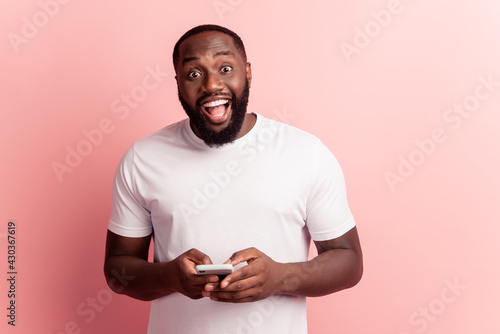 Portrait of young man hold smart phone open mouth amazed on pink wall