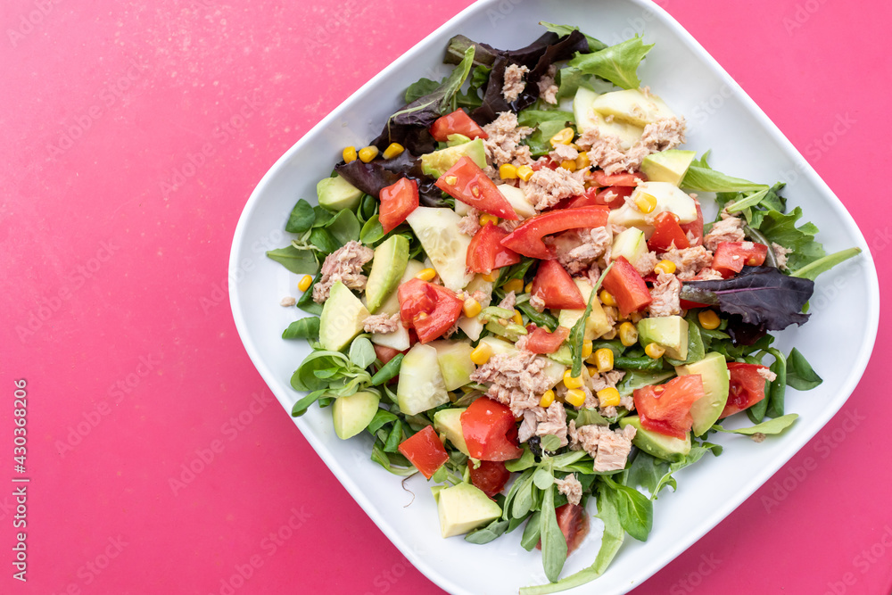 Ensalada de aguacate y verduras en plato sobre fondo rosa, comida vegetariana saludable y divertida Ensalada de aguacate y verduras en plato sobre fondo rosa, comida vegetariana saludable y divertida