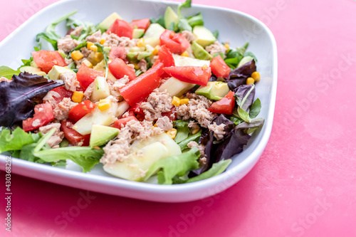 Ensalada de aguacate y verduras en plato sobre fondo rosa, comida vegetariana saludable y divertida