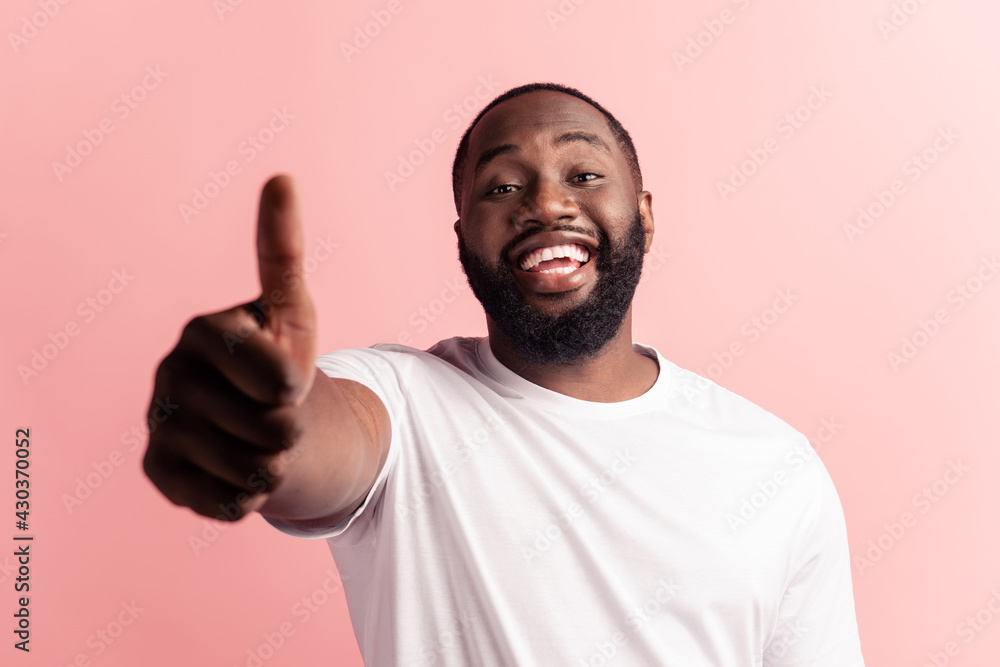 Portrait of afroamerican handsome bearded man showing thumb up sign on pink background Portrait of afroamerican handsome bearded man showing thumb up sign on pink background