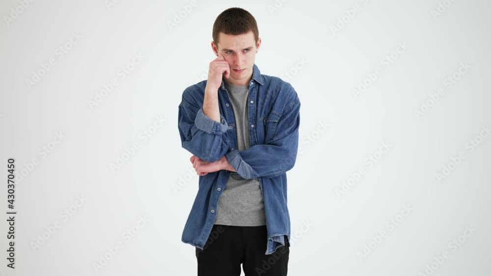 A pensive man thinking about something and scratching his head in a gray studio A pensive man thinking about something and scratching his head in a gray studio