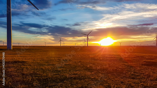 A field of wind turbines build on a vast pasture in Xilinhot in Inner Mongolia. Natural resources energy. Clean energy. Endless grassland. The sun is setting behind horizon. Golden hour. Serenity photo