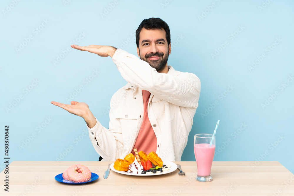 Man at a table having breakfast waffles and a milkshake holding copyspace to insert an ad Man at a table having breakfast waffles and a milkshake holding copyspace to insert an ad