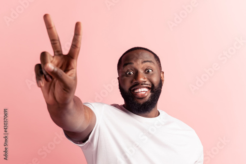 Portrait of crazy dark-skinned young man showing two fingers shiny smile look camera