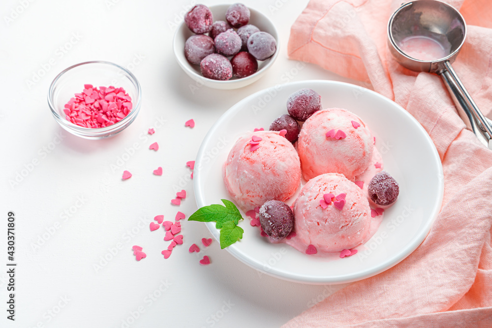 Cherry ice cream with frozen cherries on a white background with a pink napkin. Cherry ice cream with frozen cherries on a white background with a pink napkin.