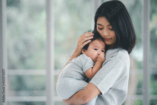 Young beautiful asian mother lifting and playing with her baby.