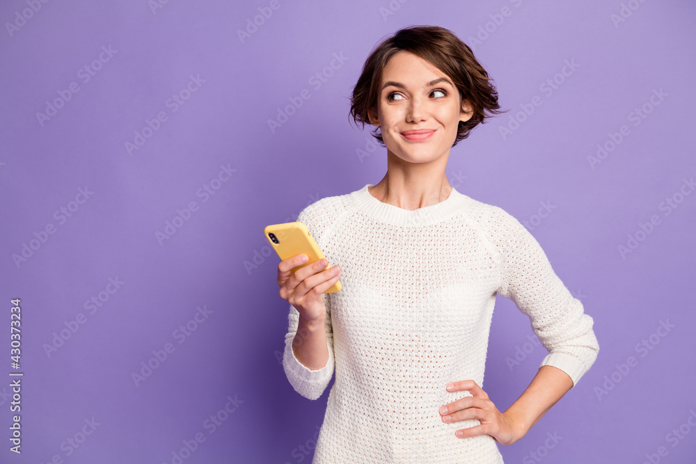 Photo portrait of curious female student looking at blank space with cellphone smiling isolated on vivid violet color background Photo portrait of curious female student looking at blank space with cellphone smiling isolated on vivid violet color background