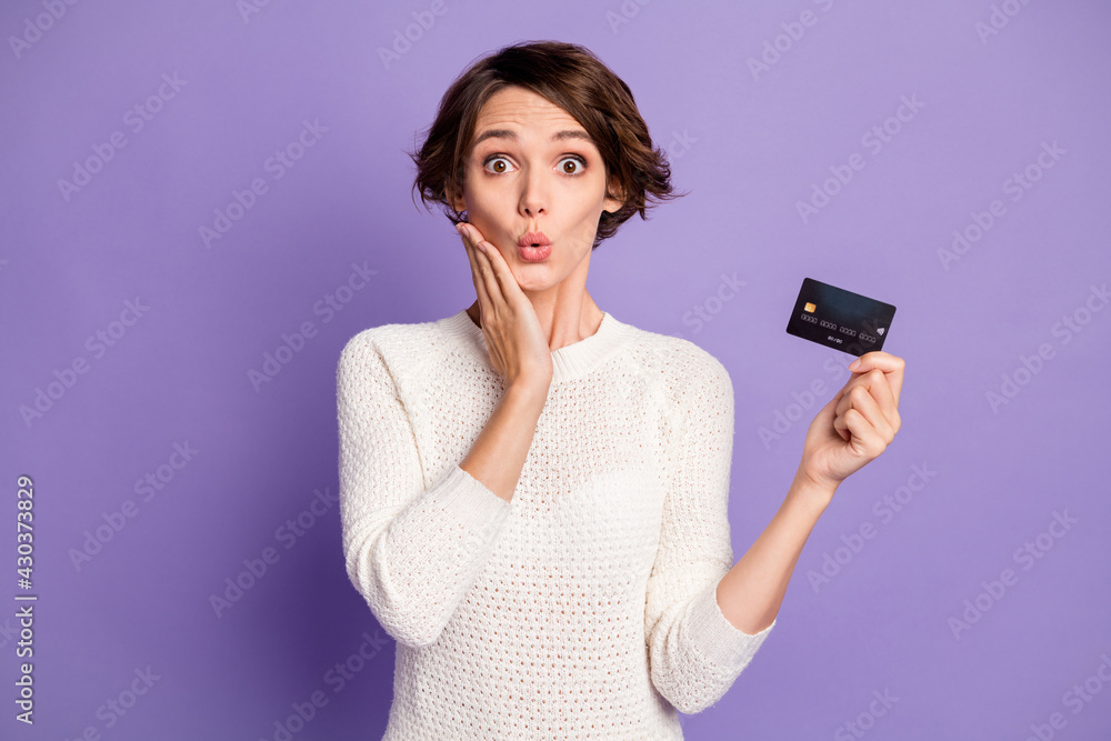 Photo portrait of amazed surprised girl with bank card touching cheek isolated on vivid purple color background Photo portrait of amazed surprised girl with bank card touching cheek isolated on vivid purple color background