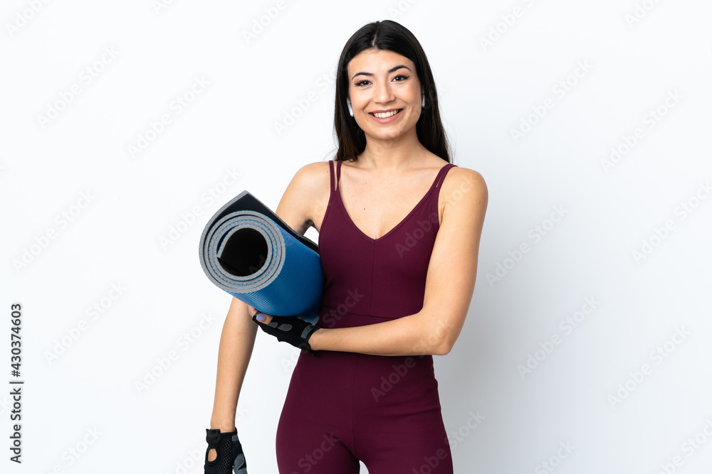 Young sport woman over isolated white background with a mat and smiling
