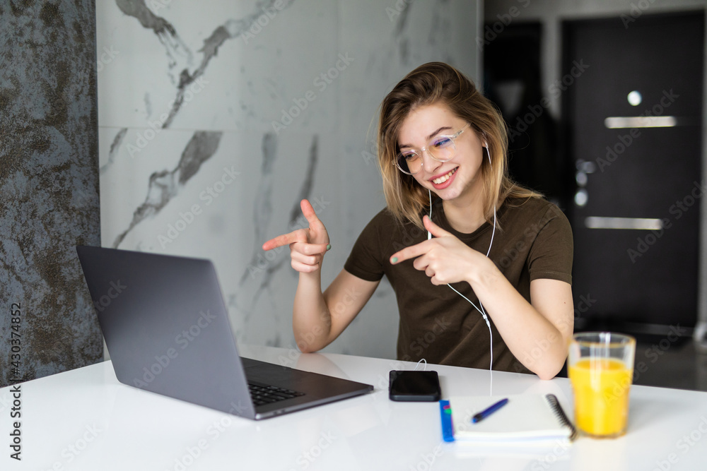 Young woman pointing at laptop screen during morning in kitchen working from home using device with technology, Young woman pointing at laptop screen during morning in kitchen working from home using device with technology,