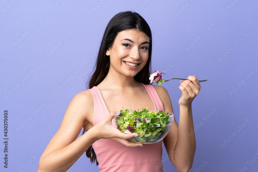 Young woman with salad over isolated purple background Young woman with salad over isolated purple background
