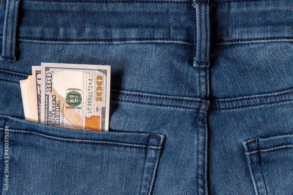 Banknotes sticking out of the back pocket of blue jeans. Close-up. Banknotes sticking out of the back pocket of blue jeans. Close-up.