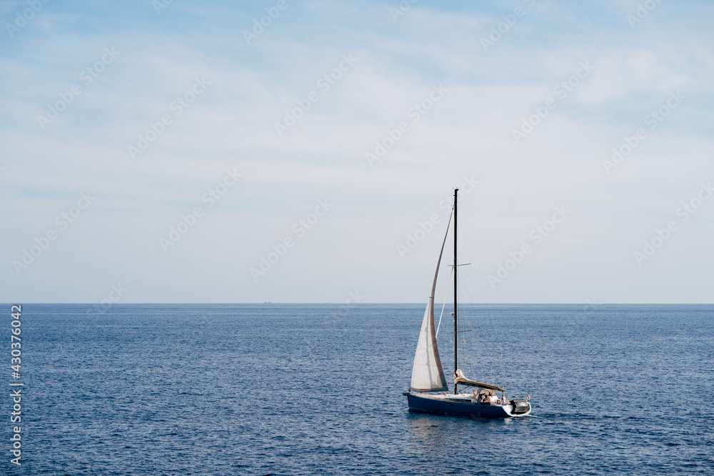 Small boat with a white sail fluttering in the wind sails on the sea