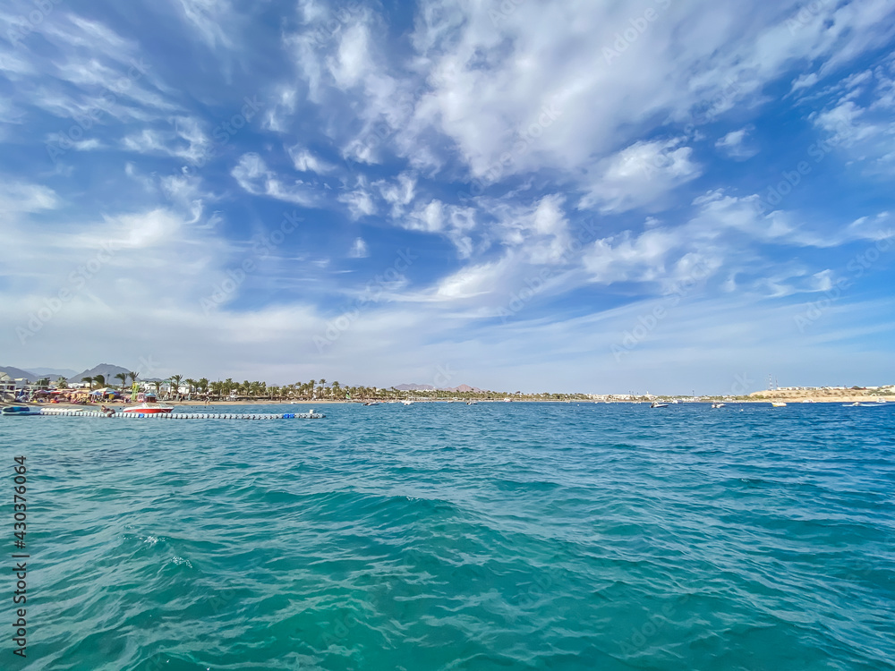 Fototapeta premium Mobile photography of the sea at Naama Bay, Red Sea and motor yachts, Sharm el Sheikh, Egypt. Resort town and beach. Blue sky with clouds. Background texture with summer concept.
