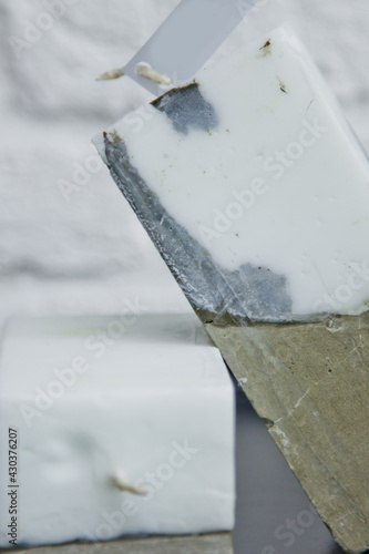 homemade white candle with concrete on the background of a white wall. handmade decor close-up. Details of colored candles in the loft style in the shape of a cube
