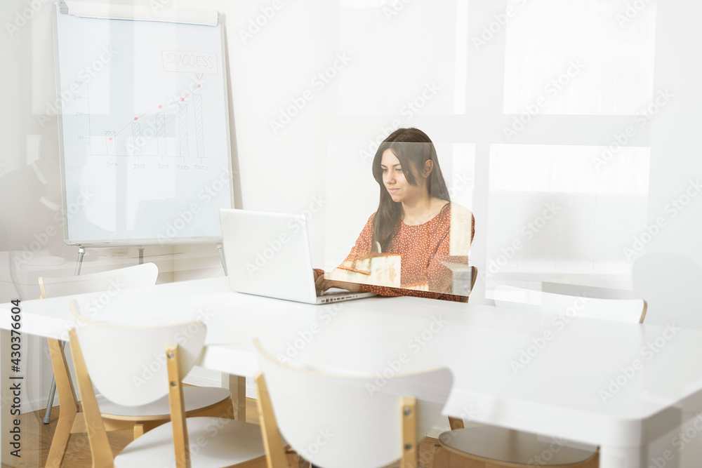 Businesswoman sitting at desk in the office working on laptop.