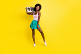Full body photo of attractive dark skin trendy woman hold cassette player wear pink singlet isolated on yellow color background