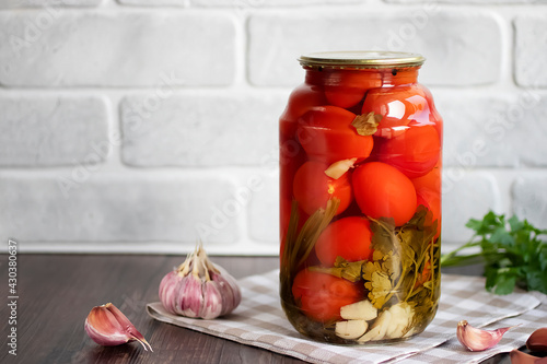 Pickled tomatoes in a glass jar. Homemade.