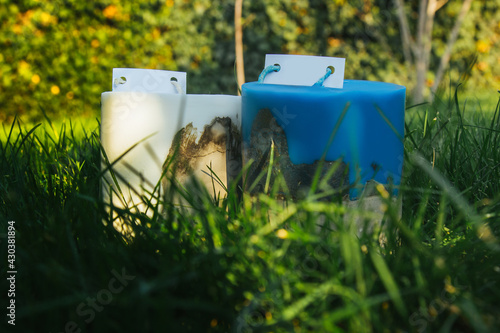 homemade multi-colored candles with concrete on a background of green grass. handmade decor close-up. Details of a colored cube and tube loft candle