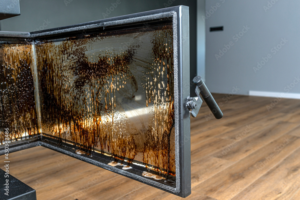 Cleaning the corner glass from soot in a modern fireplace with a closed