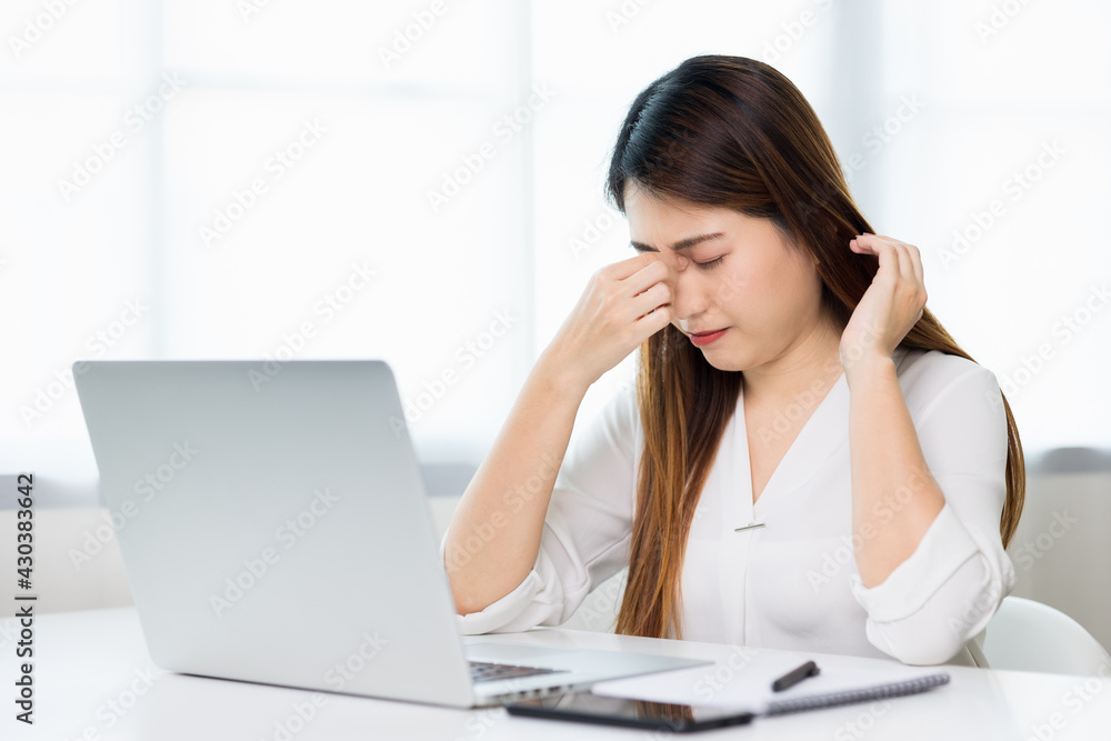 Young asian business woman rubbing her eyes she's feeling depressed stress headache be tired from working with laptop a long time she symptom office syndrome. Young asian business woman rubbing her eyes she's feeling depressed stress headache be tired from working with laptop a long time she symptom office syndrome.