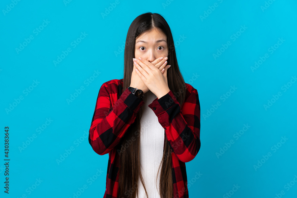 Young Chinese girl over isolated blue background covering mouth with hands Young Chinese girl over isolated blue background covering mouth with hands