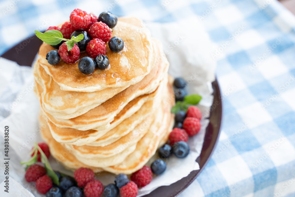 Pancakes with honey and berries on blue background Pancakes with honey and berries on blue background