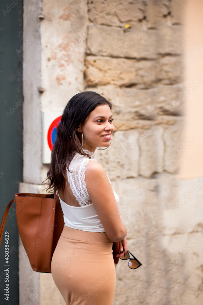 young woman smiling as she strolls through the streets of europe young woman smiling as she strolls through the streets of europe