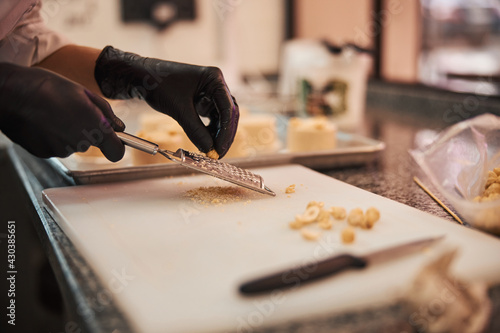 Qualified confectioner grating hazel-nuts on a cutting board photo