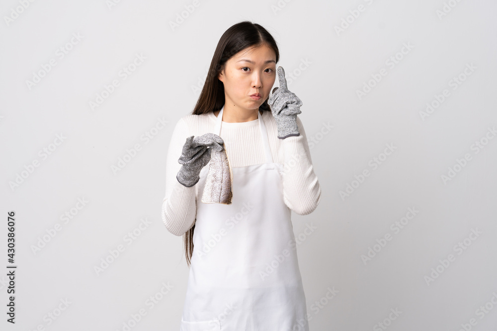 Chinese fishmonger wearing an apron and holding a raw fish over isolated white background thinking an idea Chinese fishmonger wearing an apron and holding a raw fish over isolated white background thinking an idea