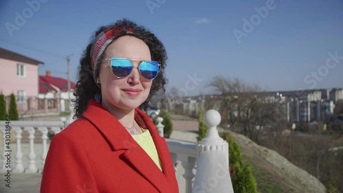 Pretty smiling curly woman in stylish look confidently sunglasses