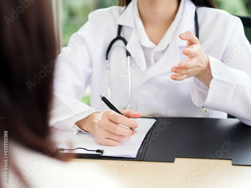 A close-up of the hand of a female doctor or nurse holding a pen is talking or explaining information or something for a patient...