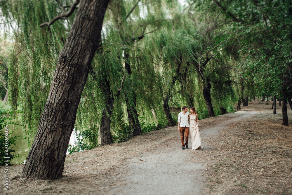 Fototapeta premium a guy and a girl are walking along the banks of a wild river overgrow