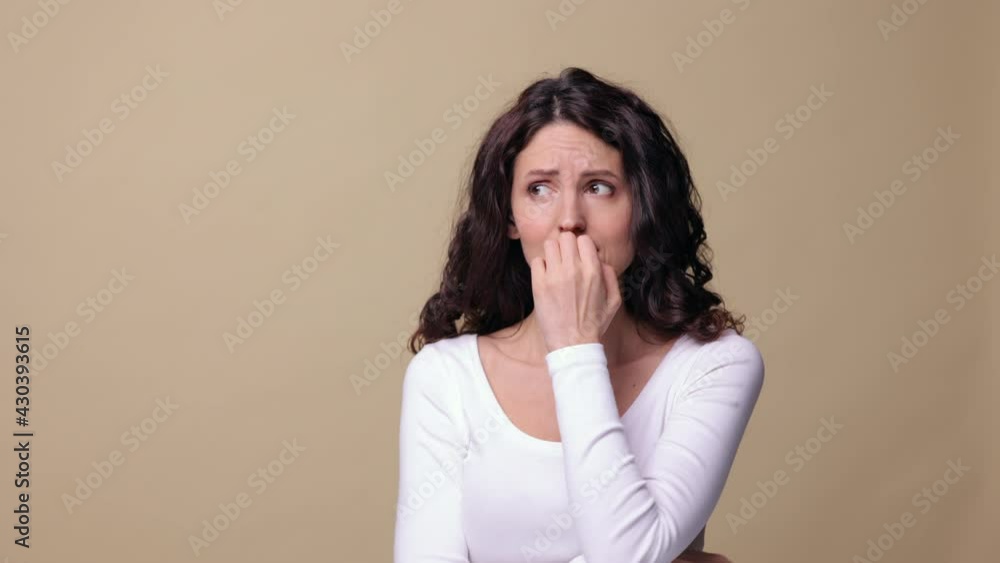 Nervous terrified female scared, biting nails in panic isolated over beige studio background. Insecure millennial woman feel anxious about problem, uncertain and confused. Stress and anxiety concept Nervous terrified female scared, biting nails in panic isolated over beige studio background. Insecure millennial woman feel anxious about problem, uncertain and confused. Stress and anxiety concept