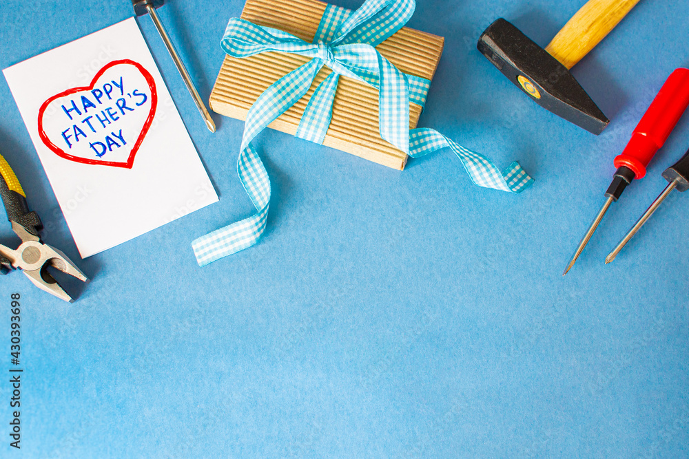 Fototapeta premium Happy father day. Blue background with tools, give dad a present and a heart with the inscription: Happy Father's Day . Copy space for text.