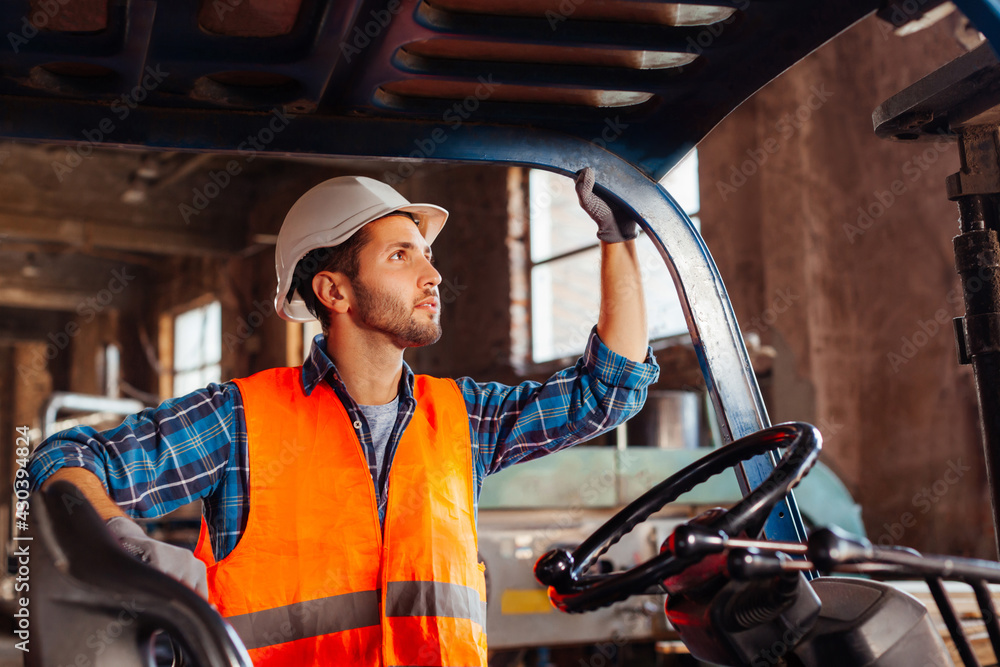 Young confident warehouse worker posing in a forklift truck Young confident warehouse worker posing in a forklift truck