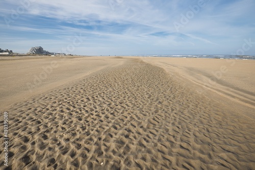 Horizontal landscape of special structures in the sand, beach and sea on a sunny day. Ribbed sand pattern. With copy space.