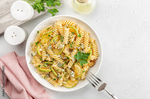 Pasta fusilli with zucchini and gorgonzola cheese on light table.