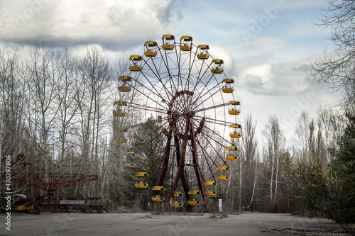 Old abandoned rusty metal radioactive yellow ferris wheel against dramatic sky in amusement park in ghost town Pripyat, Chernobyl Exclusion Zone