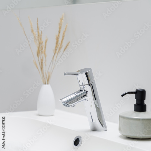 Close-up on silver tap in bathroom washbasin photo