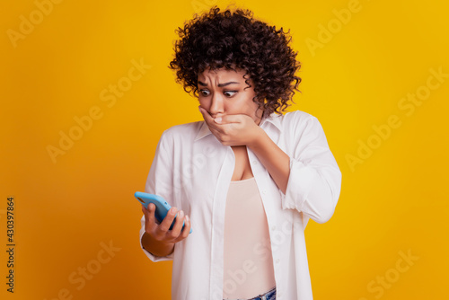 Close up portrait of shocked african american woman hold telephone close mouth