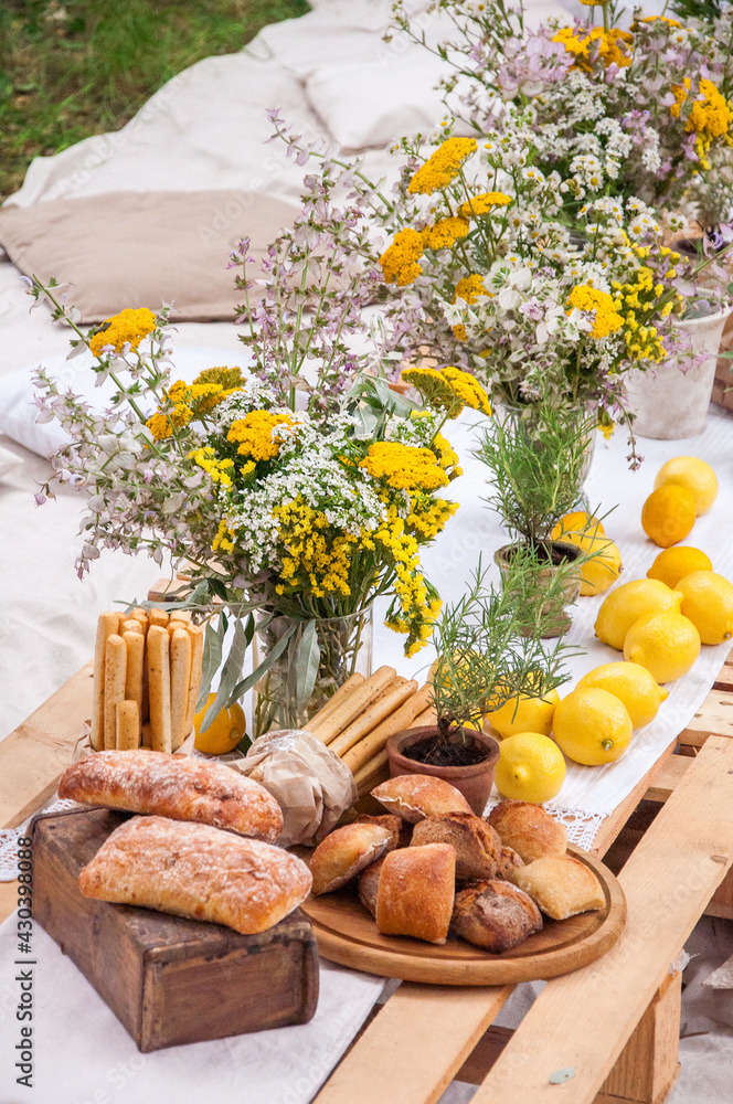 Fototapeta premium Bread of ciabatta, lemons, flowers on a picnic