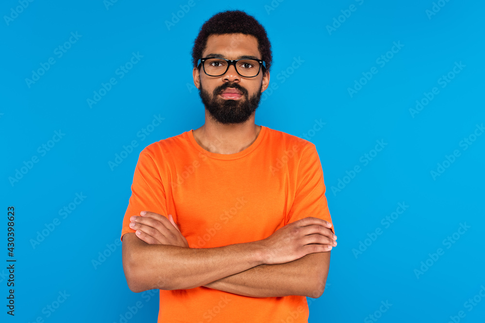 bearded african american man in glasses with crossed arms isolated on blue bearded african american man in glasses with crossed arms isolated on blue