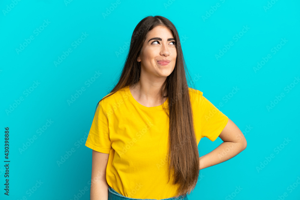 Young caucasian woman isolated on blue background having doubts while looking up Young caucasian woman isolated on blue background having doubts while looking up
