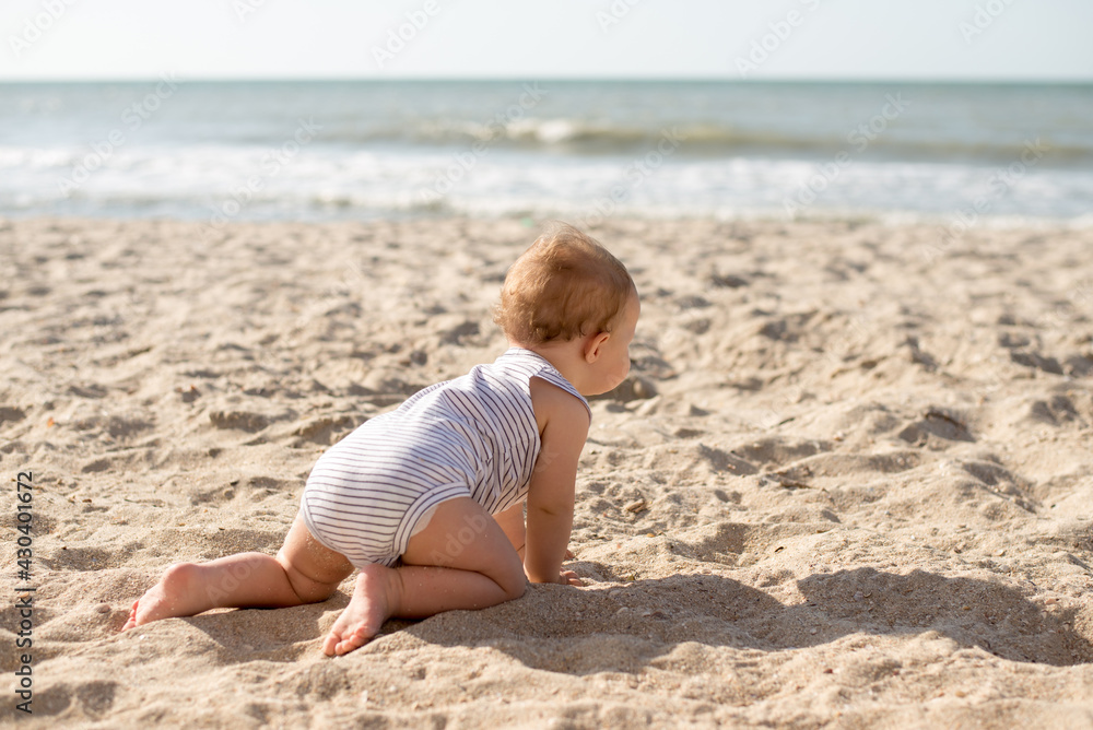 Small girl crawls on sand at beach near the sea Small girl crawls on sand at beach near the sea