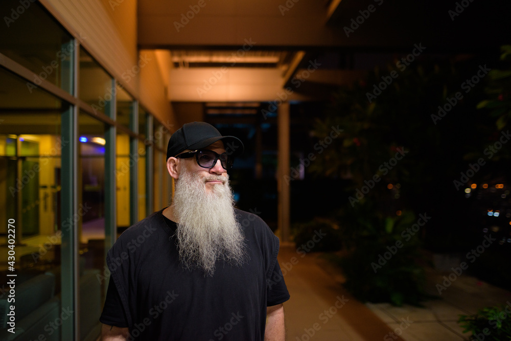 Obraz premium Portrait of mature man with gray beard outdoors at night thinking