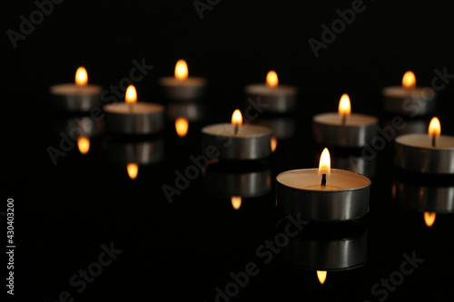 Small burning candles on table in darkness, space for text