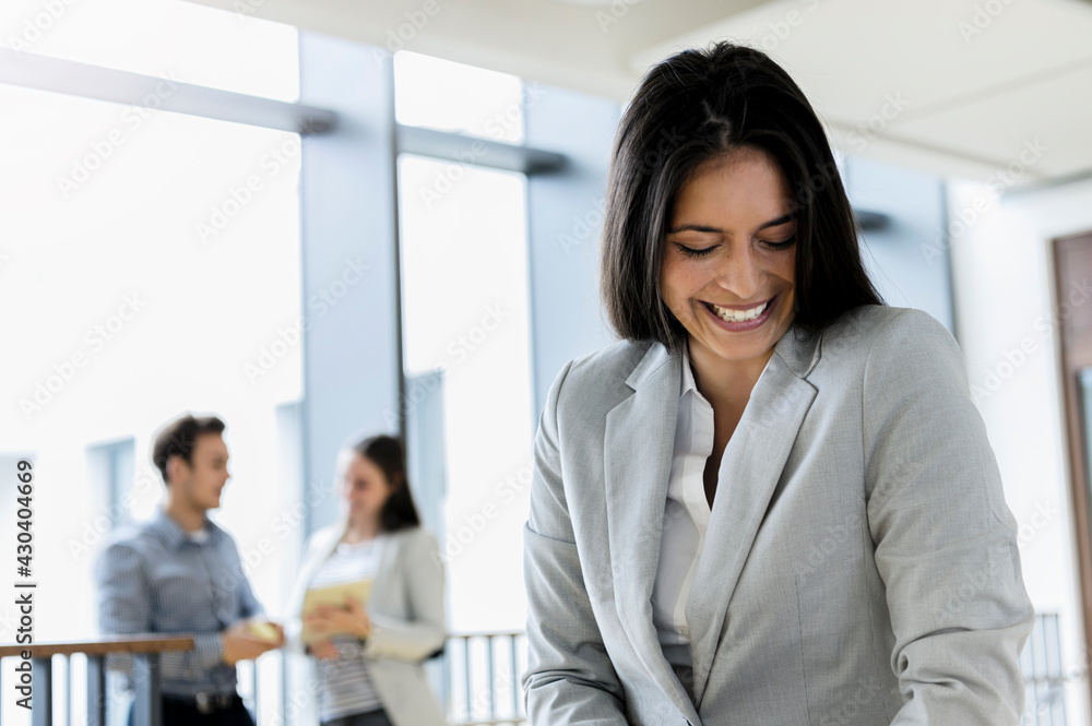 Germany, Bavaria, Munich, Smiling young businesswoman standing in corridor Germany, Bavaria, Munich, Smiling young businesswoman standing in corridor