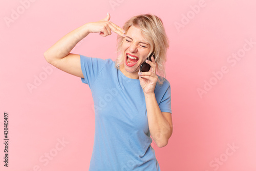 young pretty woman looking unhappy and stressed, suicide gesture making gun sign. cell concept photo